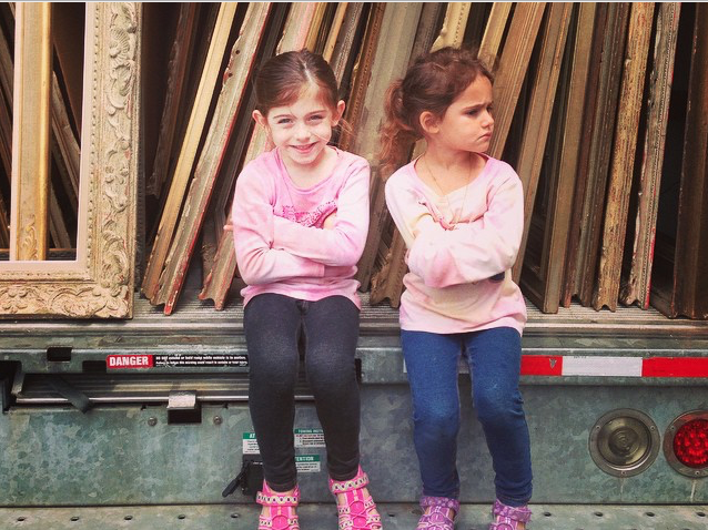 Heather Karlie Vieira's daughters sitting on the tailgate of a Rental truck filled with over 200 antique, period and modernist picture frames