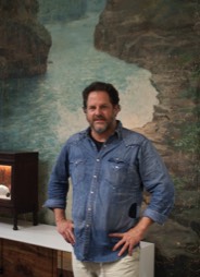 Photo of Tyler Hays of BDDW in front of an antique hand painted wall mural on canvas sourced by Heather Karlie Vieira
